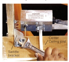 4. Secure saddle brackets to the center ceiling joist with nuts and bolts. Make sure the fan is centered before you drill holes in the joist.